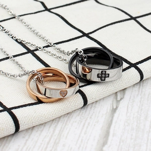 Close-up of titanium steel interlocking double ring necklaces with heart and cross accents