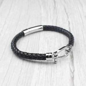 Bracelet tressé en cuir noir fait main avec fermoir argenté sur fond en bois