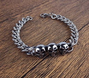 Détail de trois têtes de mort en acier inoxydable sur un bracelet gourmette épais
