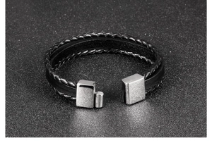 Macro shot of a multi-layer black braided leather bracelet for men with silver metal buckle