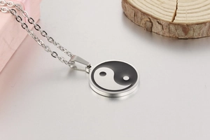 Detailed view of the Yin Yang pendant with polished silver finish on a wooden background