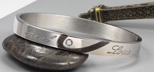 Close-up of titanium steel bangle with Real Love engraving and a sparkling zircon stone