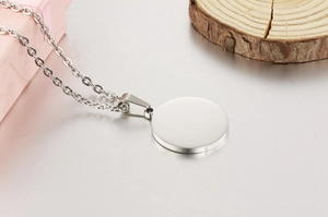 Macro detail of polished stainless steel round pendant and O-chain on wooden base