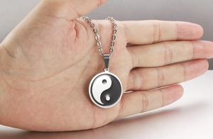 Detailed view of stainless steel Tai Chi Yin Yang pendant necklace held in hand