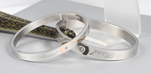 Macro detail of brushed titanium steel bracelets with Real Love engraving and small diamond