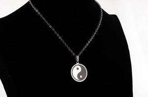 Detail of Yin Yang Tai Chi pendant on a black metal chain shown on a model bust