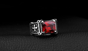 Macro detail of a gothic stainless steel ring with a large red zircon stone and cross relief