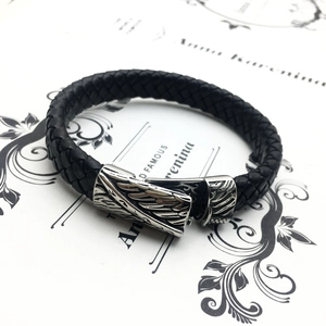 Men's braided leather bracelet with vintage silver feather clasp on decorative paper