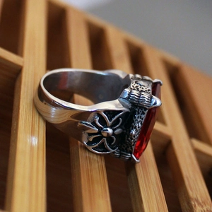Detail of vintage men's titanium ring with red ruby stone and eagle claw cross pattern