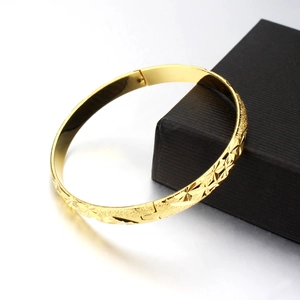 Elegant 18K gold open cuff bracelet with star engravings and a luxury black jewelry box