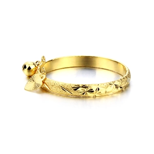 Detail of 18K gold-plated kid's bangle with frosted star patterns and small bell charms