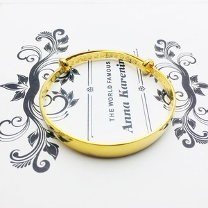 Polished 18K gold plated wide bangle with interior embossed pattern on vintage card