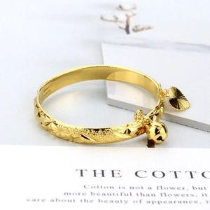 Gold plated open bangle for children with bell and heart charms and geometric engraving