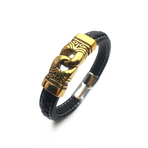 Close-up of men's black braided leather bracelet with gold totem metal ornament and magnetic clasp