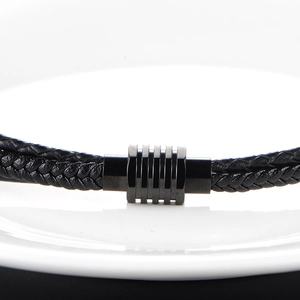 Macro detail of men's black woven leather bracelet with textured metal industrial clasp
