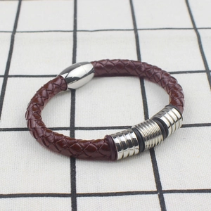Close-up of brown braided leather men's bracelet with polished silver metal accents