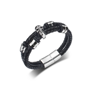 Detail of woven black leather bracelet featuring silver skull and polished steel magnetic clasp