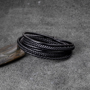 Detail of handcrafted multi-layer black leather bracelet on textured stone background