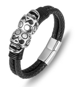 Detail of black braided leather bracelet featuring silver skull charms and magnetic clasp