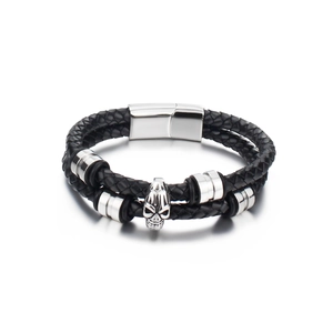 Detail of black double-layer braided leather bracelet with silver skull charm and magnetic clasp