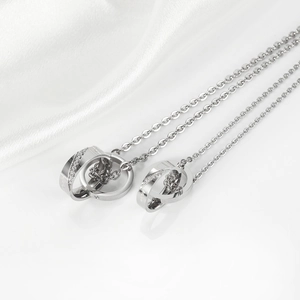 Close-up of interlocking silver double ring pendants with zircon stones on silk background