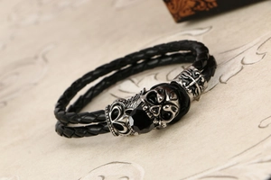 Dettaglio macro del bracciale in pelle punk con teschio e perline a croce d'argento