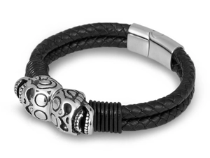 Detail of men's double-braided black leather bracelet with silver skull metal charms