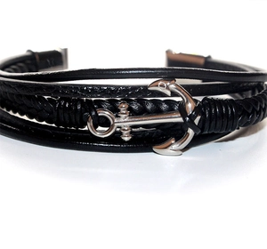 Macro detail of men's multilayer black leather bracelet with silver anchor charm