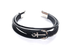 Macro detail of multi-layer black braided leather bracelet with silver anchor charm