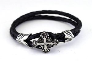Macro shot of men's black braided leather bracelet with silver zircon cross and Greek key pattern