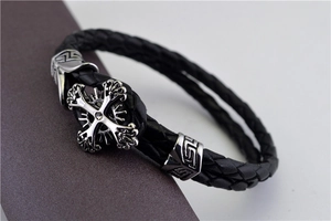 Macro shot of men's black woven leather bracelet with a silver zircon cross detail