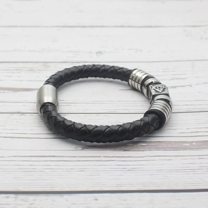 Detailed macro view of woven leather men's bracelet with Masonic symbol and metal magnetic clasp