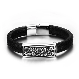 Macro detail of men's leather bracelet showing skull relief and braided texture