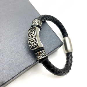 Detail eines Herrenarmbands aus schwarzem Leder mit gravierten Metallelementen
