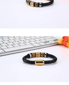 Close-up of braided black leather bracelet with metallic beads and gold magnetic clasp