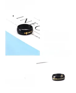 Detail of black stainless steel ring featuring golden hollow cross design and wavy lines