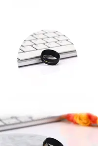 Detail of black titanium steel ring featuring gold cross motif on a tech keyboard background