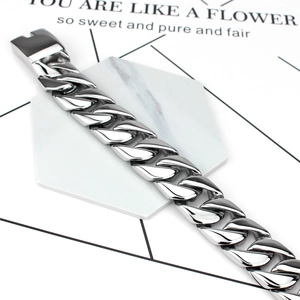 Close-up of silver-tone stainless steel Cuban link bracelet with rectangular clasp on marble