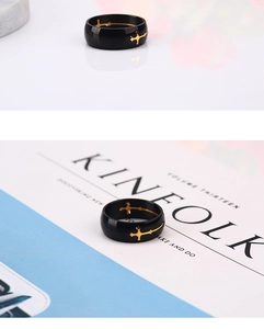 Detail of a black titanium steel ring featuring a gold cross on a minimalist magazine