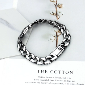 Detailed close-up of men's vintage steel Cuban link bracelet with engraved patterns