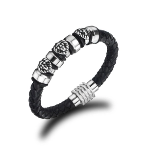 Macro detail of men's black braided leather bracelet featuring three silver lion head charms
