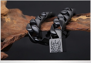 Gros plan d'un bracelet punk en titane noir mat avec un fermoir gravé d'un totem de crâne