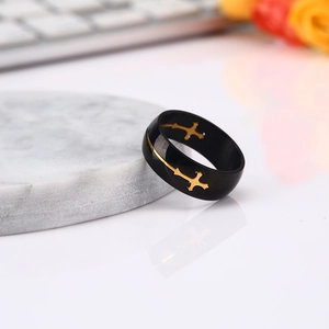Men's black stainless steel ring with golden hollow cross design on marble stand