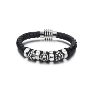 Close-up of black braided leather bracelet featuring silver lion head charms and metal clasp