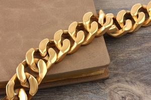Close-up of a chunky golden polished titanium steel chain on a leather notebook