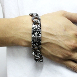 Close-up of vintage steel curb chain bracelet with engraved cross and baroque patterns