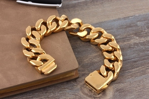 Detailed close-up of thick golden Cuban link bracelet with large square buckle on wooden desk