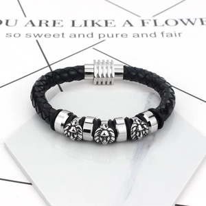 Macro detail of men's black braided leather bracelet featuring silver lion head charms