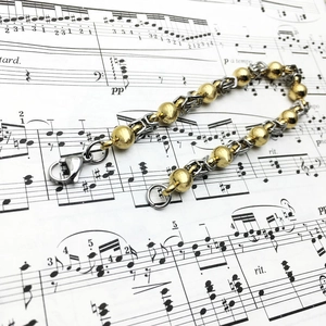 8mm Edelstahlarmband mit Goldperlen und Karabinerverschluss auf Vintage-Hintergrund