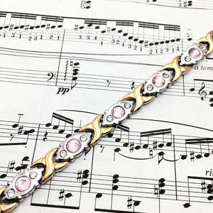 Bracelet magnétique XO bicolore en acier inoxydable avec pierre rose sur partition de musique